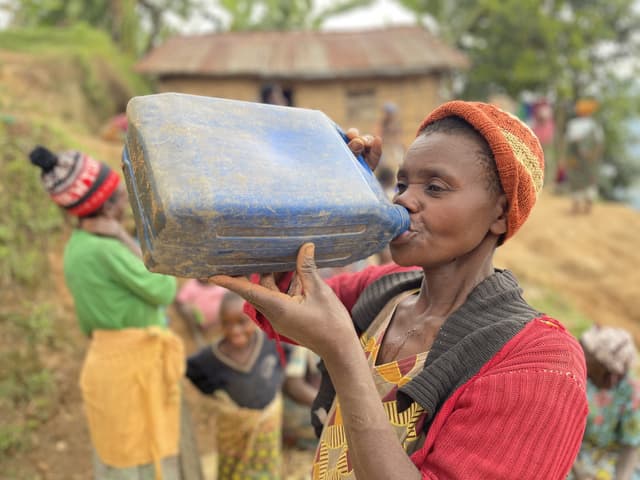 A woman drinking from a dirty jerrycan